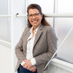 Person in a modern, light work environment wearing a grey blazer.