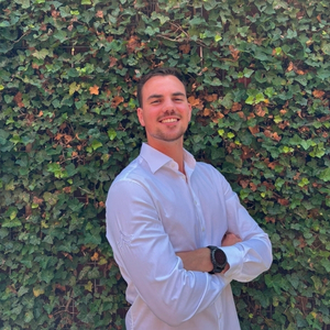 Man in white blouse standing before green wall
